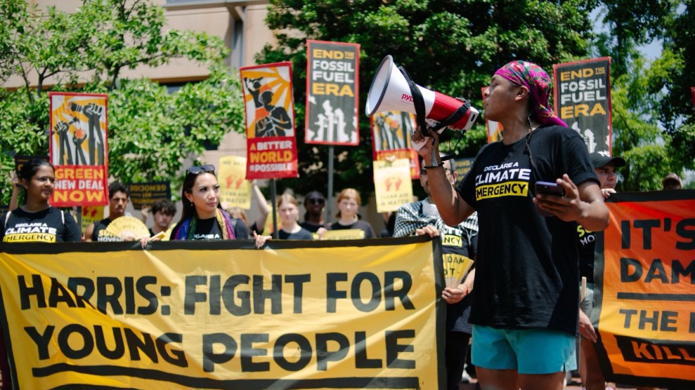 A person holds a megaphone in front of a protest crowd holding a banner that says Harris: Fight For Young People