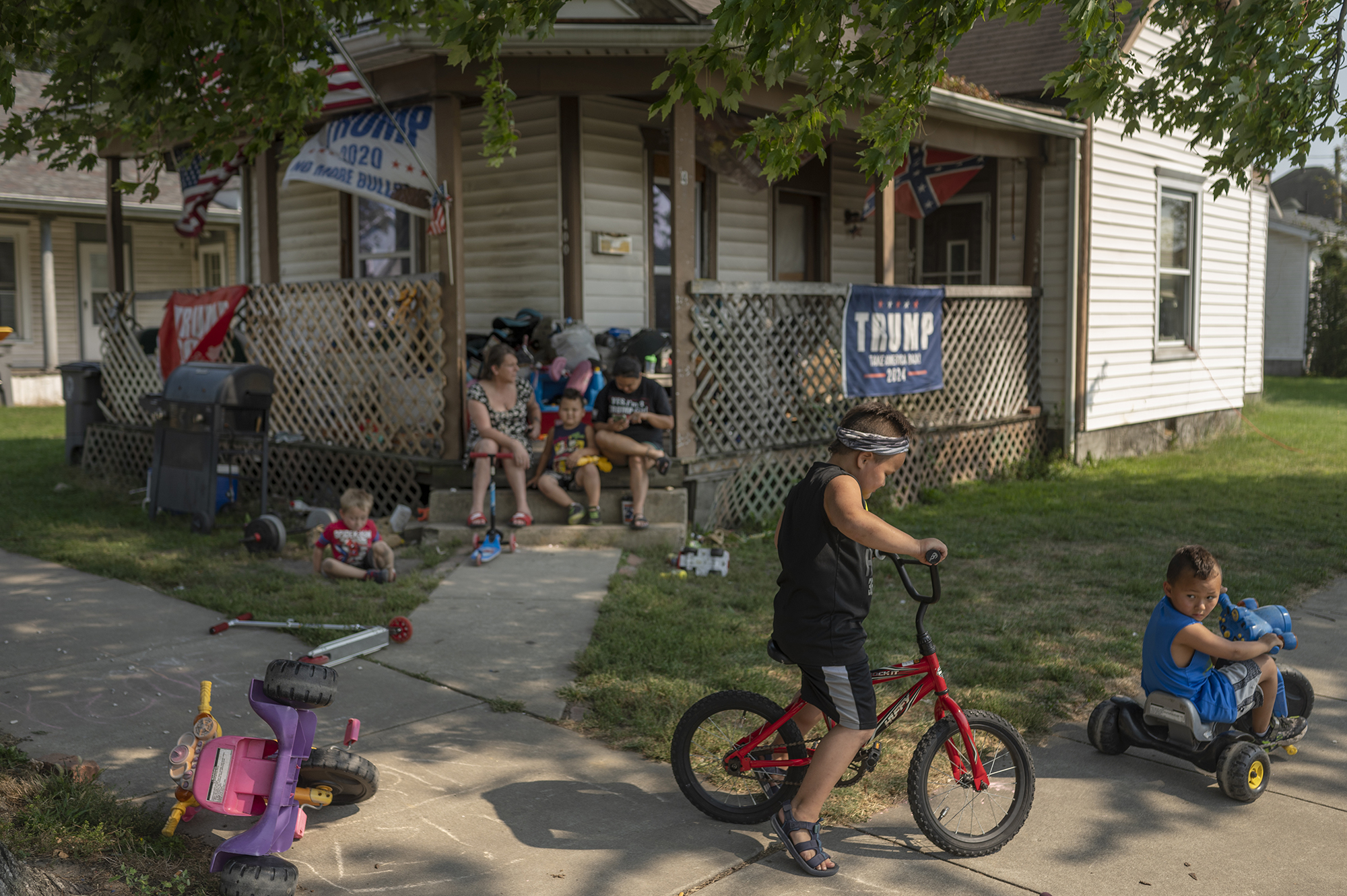 Kids play in front of a house with Trump banners hanging from the porch.