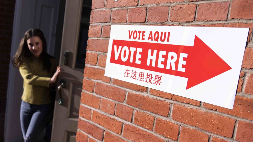 A woman exits a door next to a sign reading "Vote here" in Spanish, English, and Chinese.