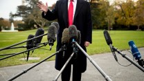 President Donald Trump speaks to members of the media—microphones are crowded before him.