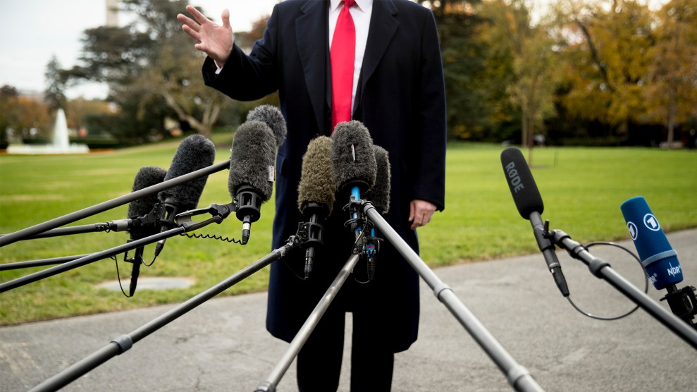 President Donald Trump speaks to members of the media—microphones are crowded before him.