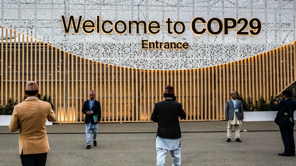 A few people gather to take photos in front of a sign that reads " Welcome to COP29"