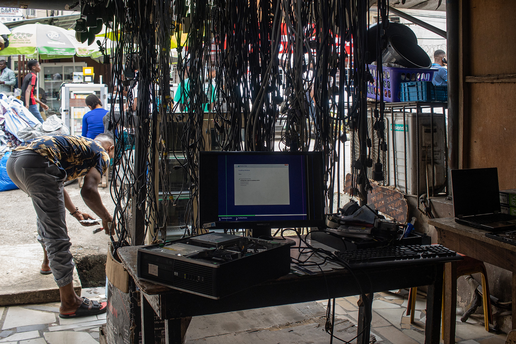 Computer screen on a desk with a tangle of cables hanging over it.