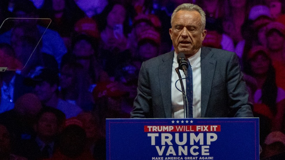 Robert Kennedy speaking behind a podium bearing a Trump-Vance sign.