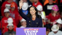 Tulsi Gabbard, a Samoan American woman in a blue suit, waves to a crowd at a Trump rally.