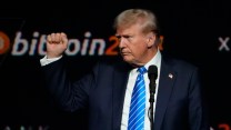 Donald Trump with raised fist in front of a "bitcoin" sign