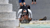 A person splashes water from a fountain onto their head.