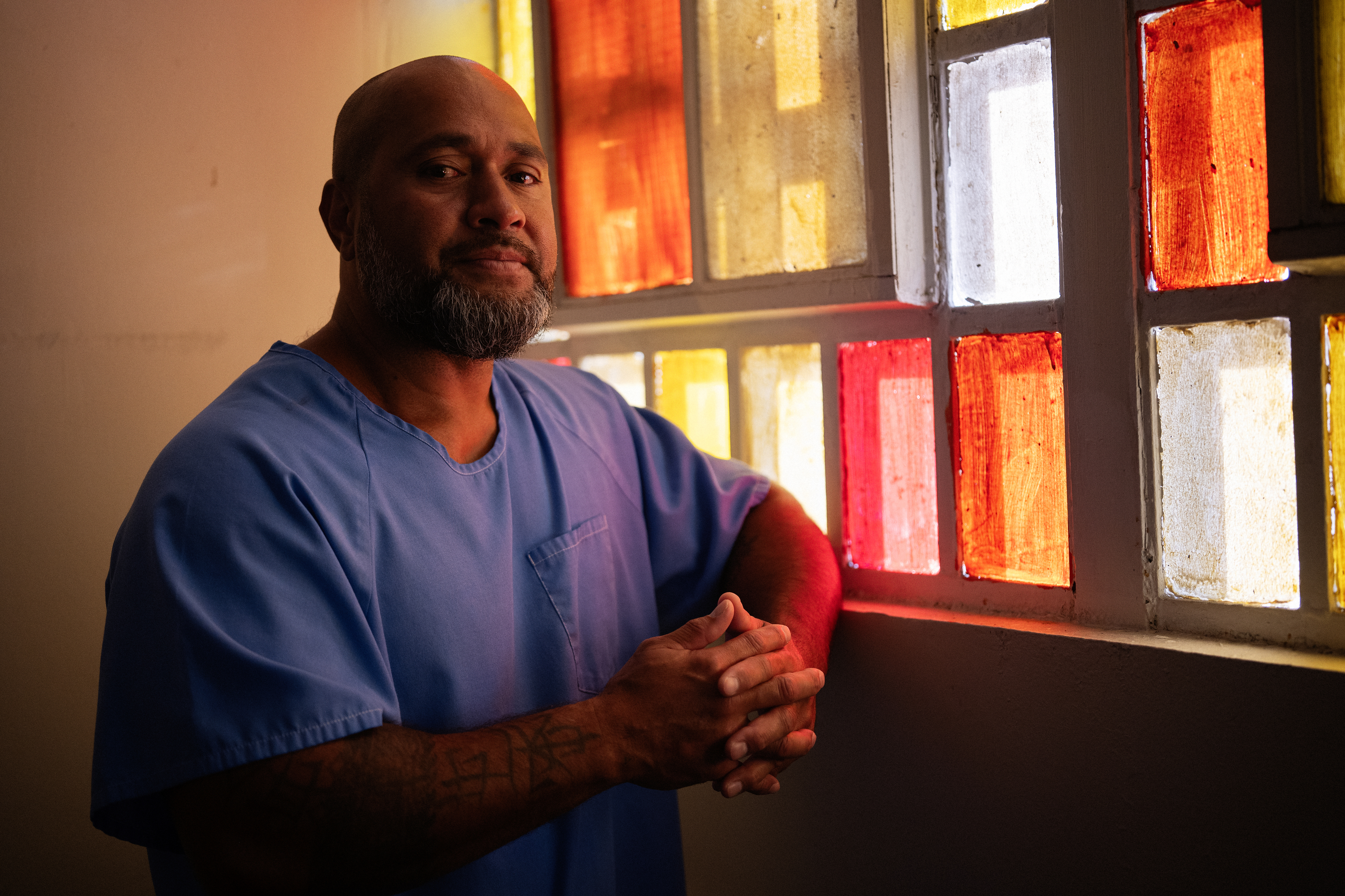 Portrait of a man standing by a stained glass window.