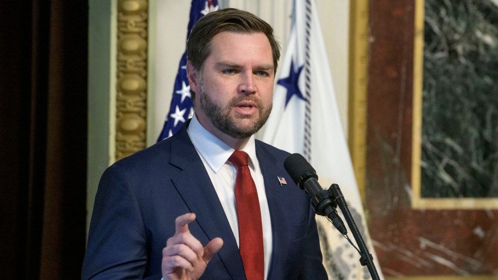 JD Vance, wearing a navy suit and red tie, stands at a microphone.