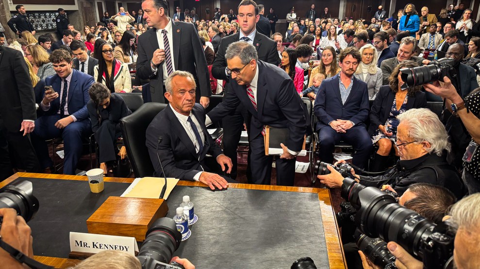 Robert F. Kennedy sits at a table, surrounded by onlookers and photographers during his confirmation hearing.