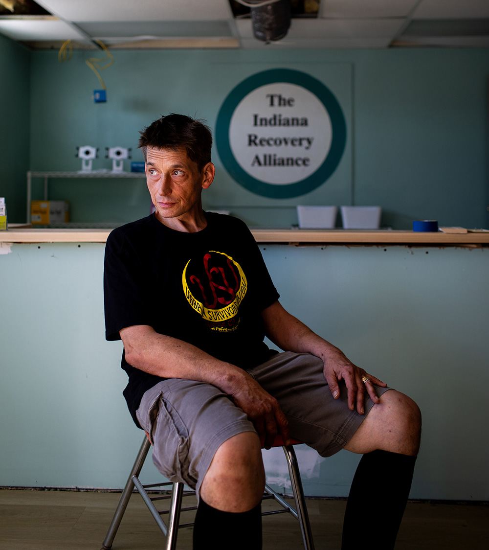 Nick Voyles sits on a chair in the lobby of a methadone clinic; he looks to the right of the camera.