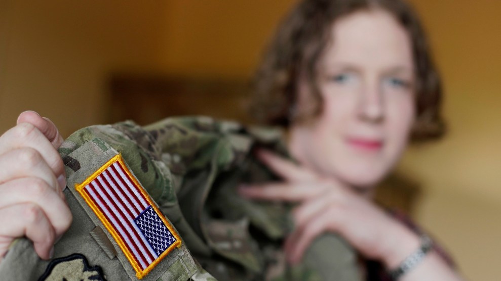 A woman with brown hair holds up a uniform with an American flag.