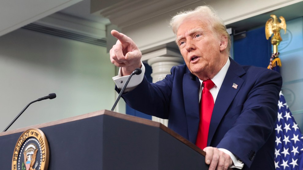 Donald Trump at a podium in a suit pointing ahead of him.