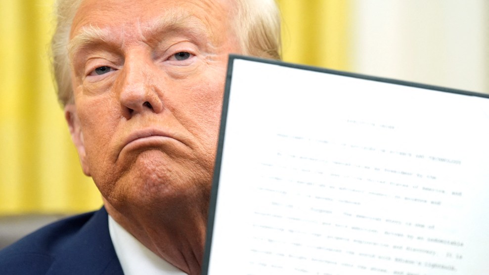 Trump frowns while holding a piece of paper.