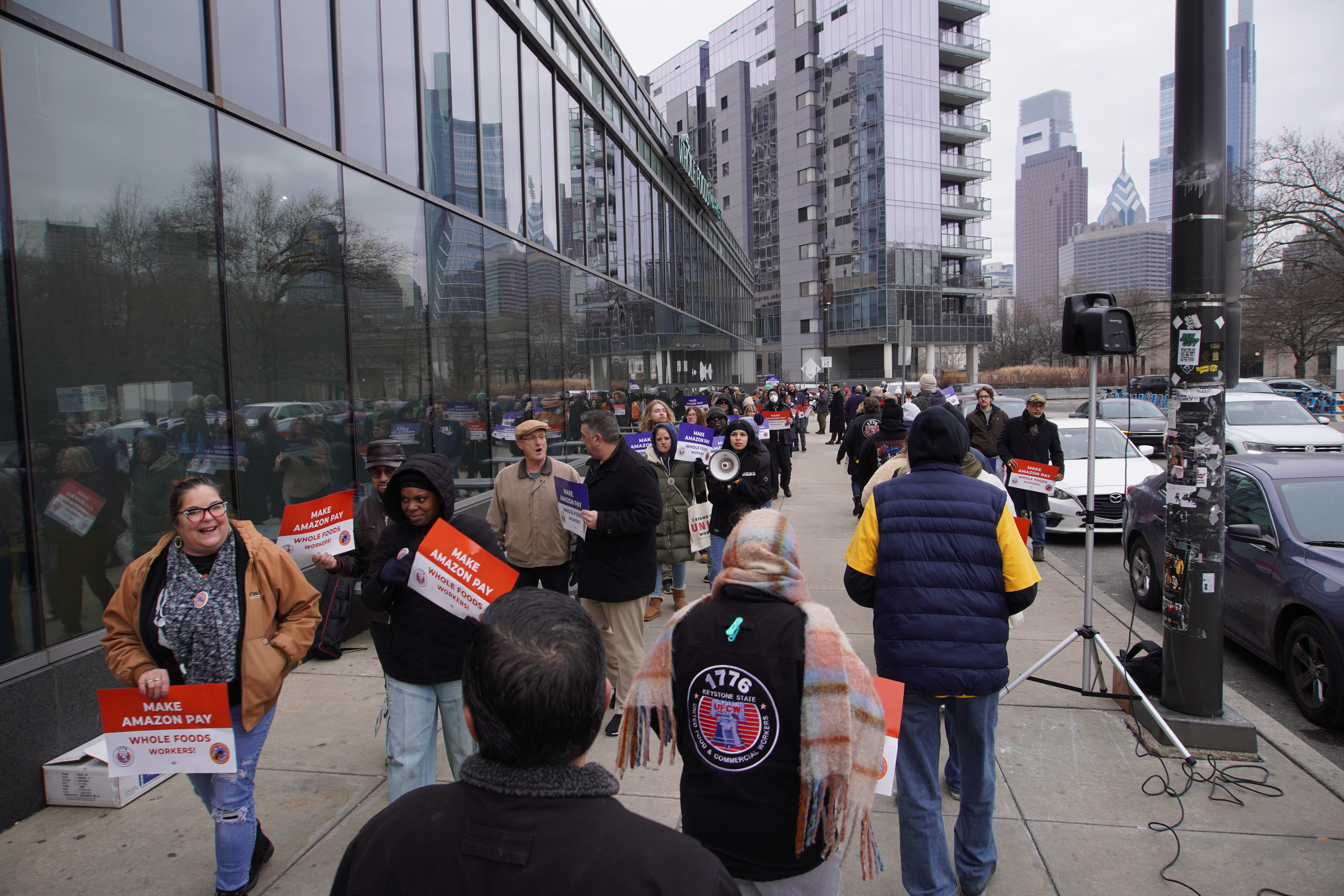 Dozens of people march on the sidewalk outside the Whole Foods store.