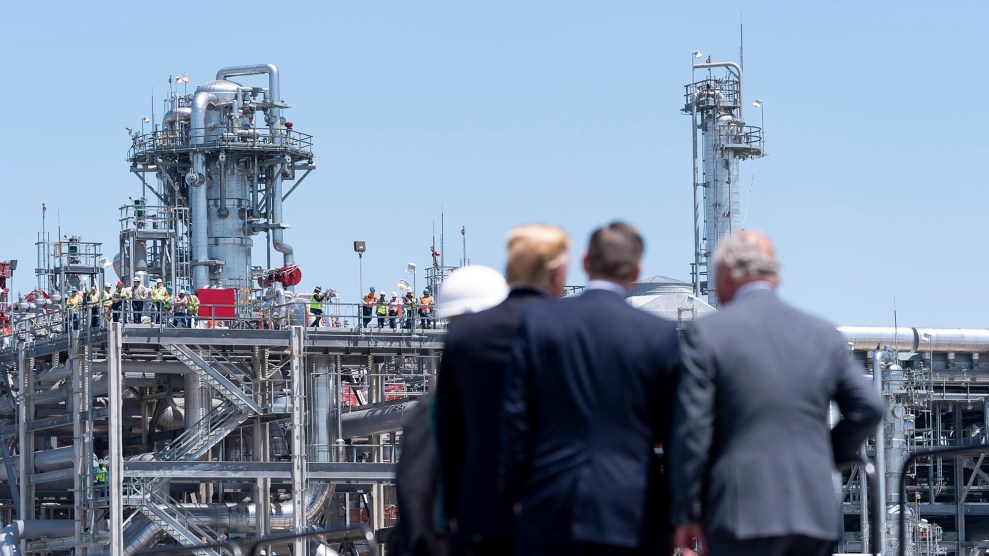 A group of men facing away from the camera looks at a large metal structure.