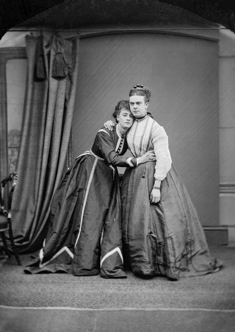 Two people wearing dresses and holding each other.