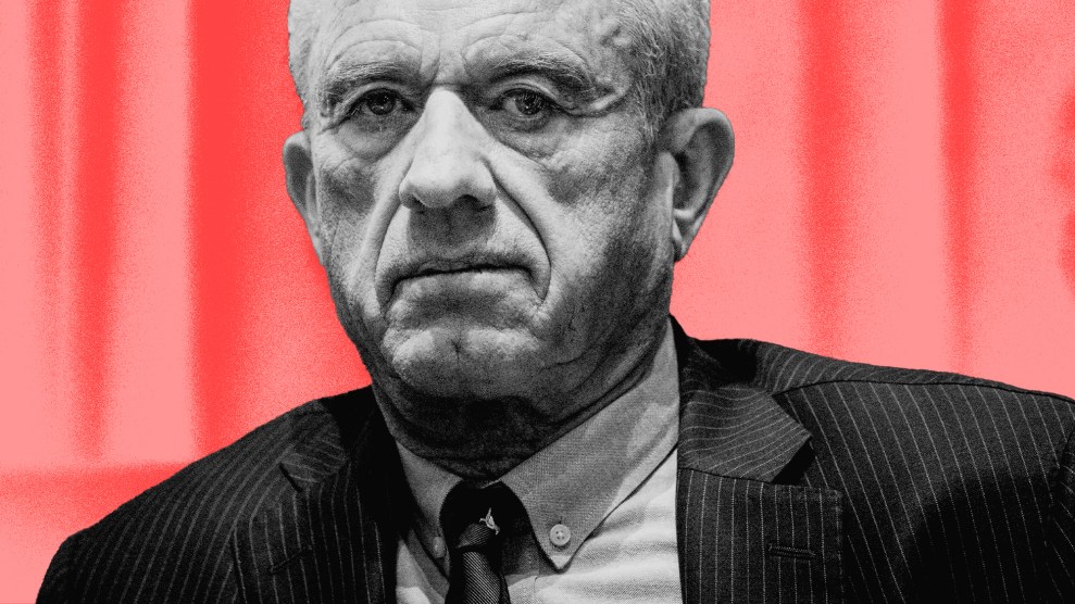 A closely cropped photo of Robert F. Kenney's face and shoulders. He is pictured in black and white while wearing a pinstripe suit and tie. His face is neutral as he stares into the distance. He is framed against a gradient background of light and dark reds.