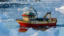 A weathered red and white boat in icy waters.