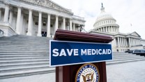 A podium with a sign that says "Save Medicaid" on it in front of a Congress building