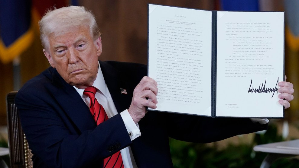 Donald Trump holds up a folder containing a signed executive order.