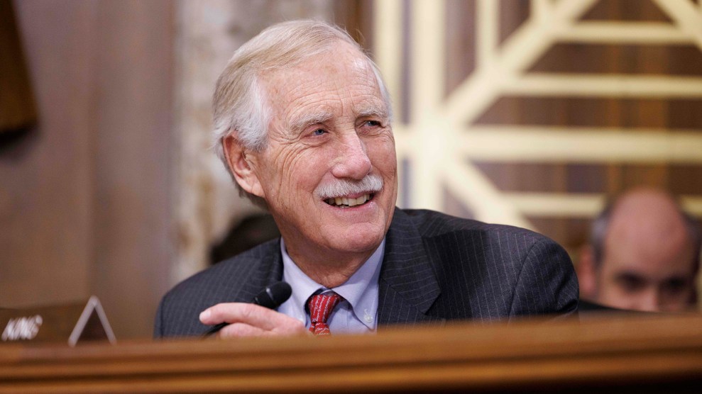 A white man with white hair and a white mustache smiles.