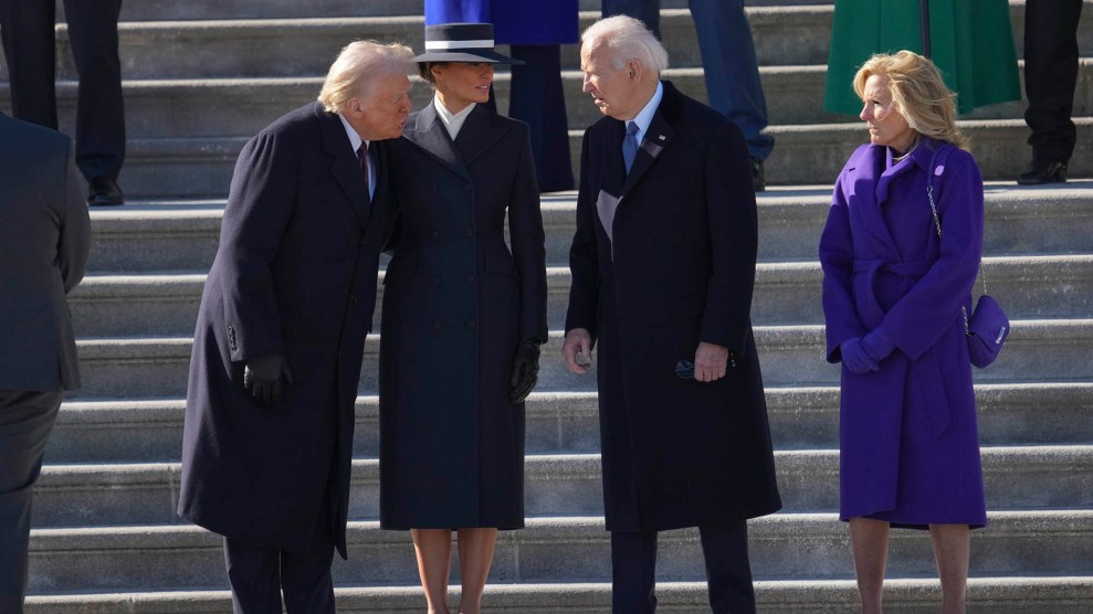 Three people wearing black jackets and one person wearing a blue jacket stand together in front of stairs.