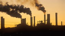 Black smokestacks next to an orange sky