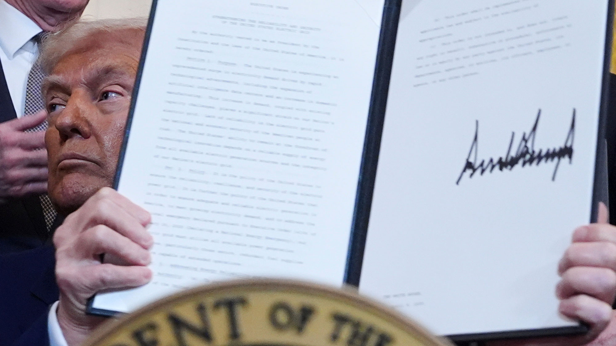 President Donald Trump holds a signed executive order