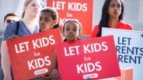 Four protesters hold signs reading "let kids be kids" and "let parents parent"