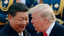 Chines man in suit smirks while a younger donald trump speaks to him privately. The regalia on soldiers uniforms can be seen in the background