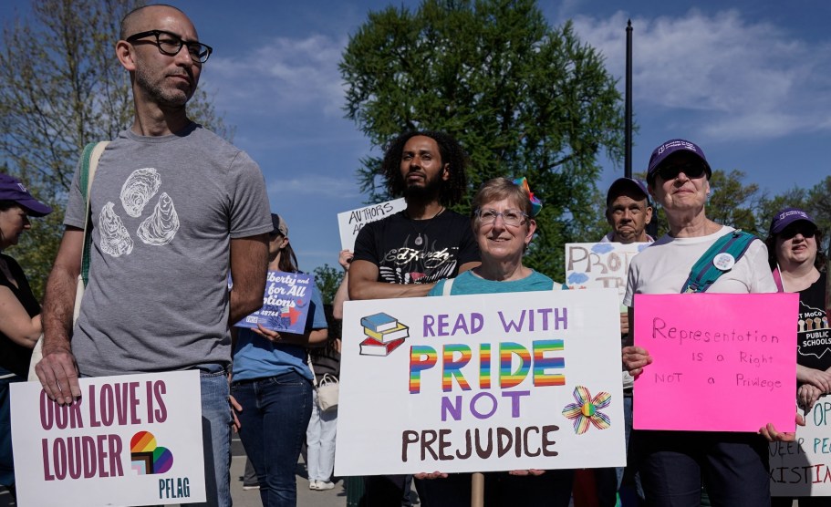 Protesters stand outside the Supreme Court building holding signs that read READ WITH PRIDE NOT PREJUDICE and REPRESENTATION IS A RIGHT NOT A PRIVILEGE.