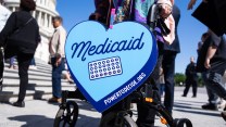 A black walker with a sign in the shape of a heart with the text Medicaid on it with some medication.
