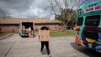 A woman unloads boxes of free reproductive health supplies from a brightly colored bus