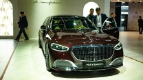 A red car is examined by men in suites.