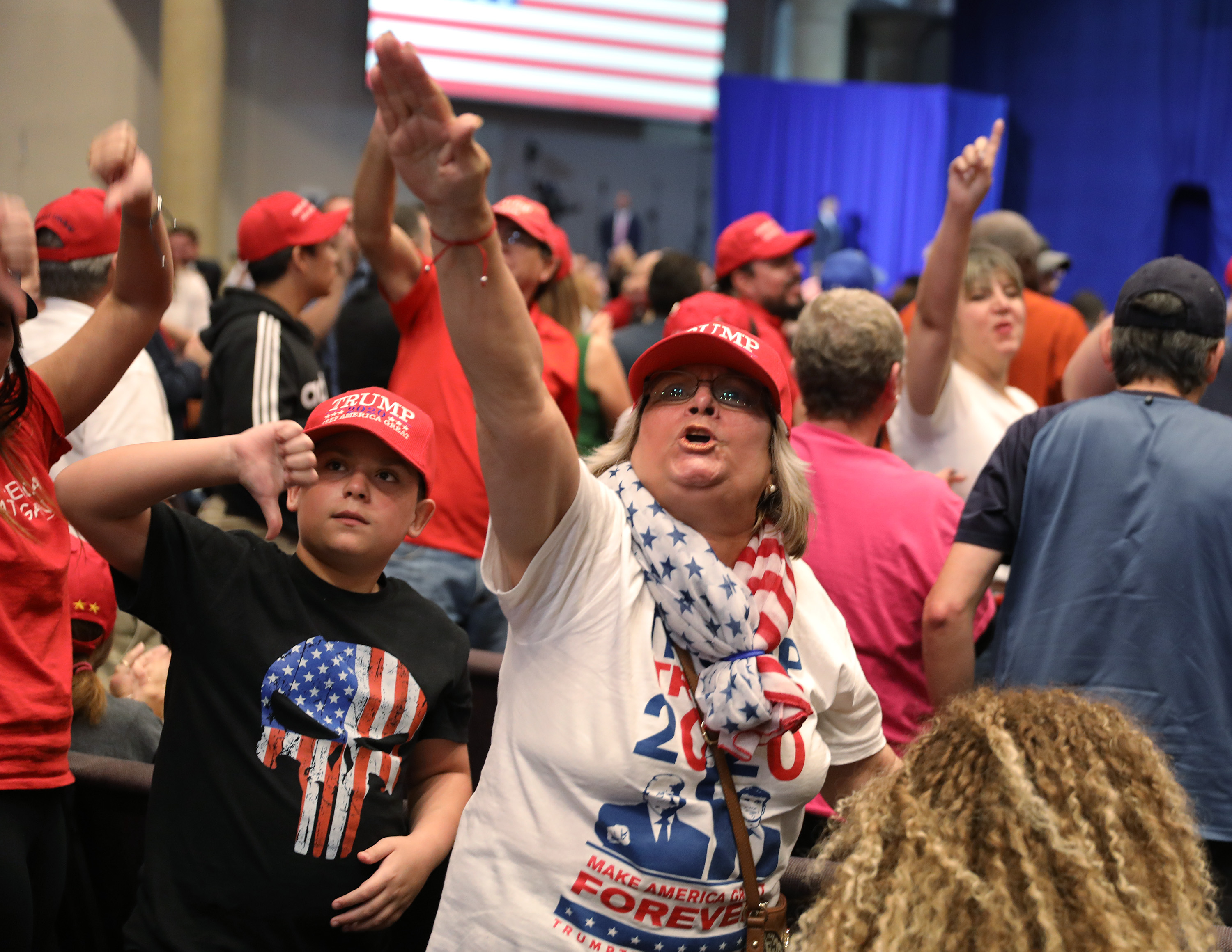 Crowd booing and making thumbs down gestures, and a woman making a nazi-like salute.