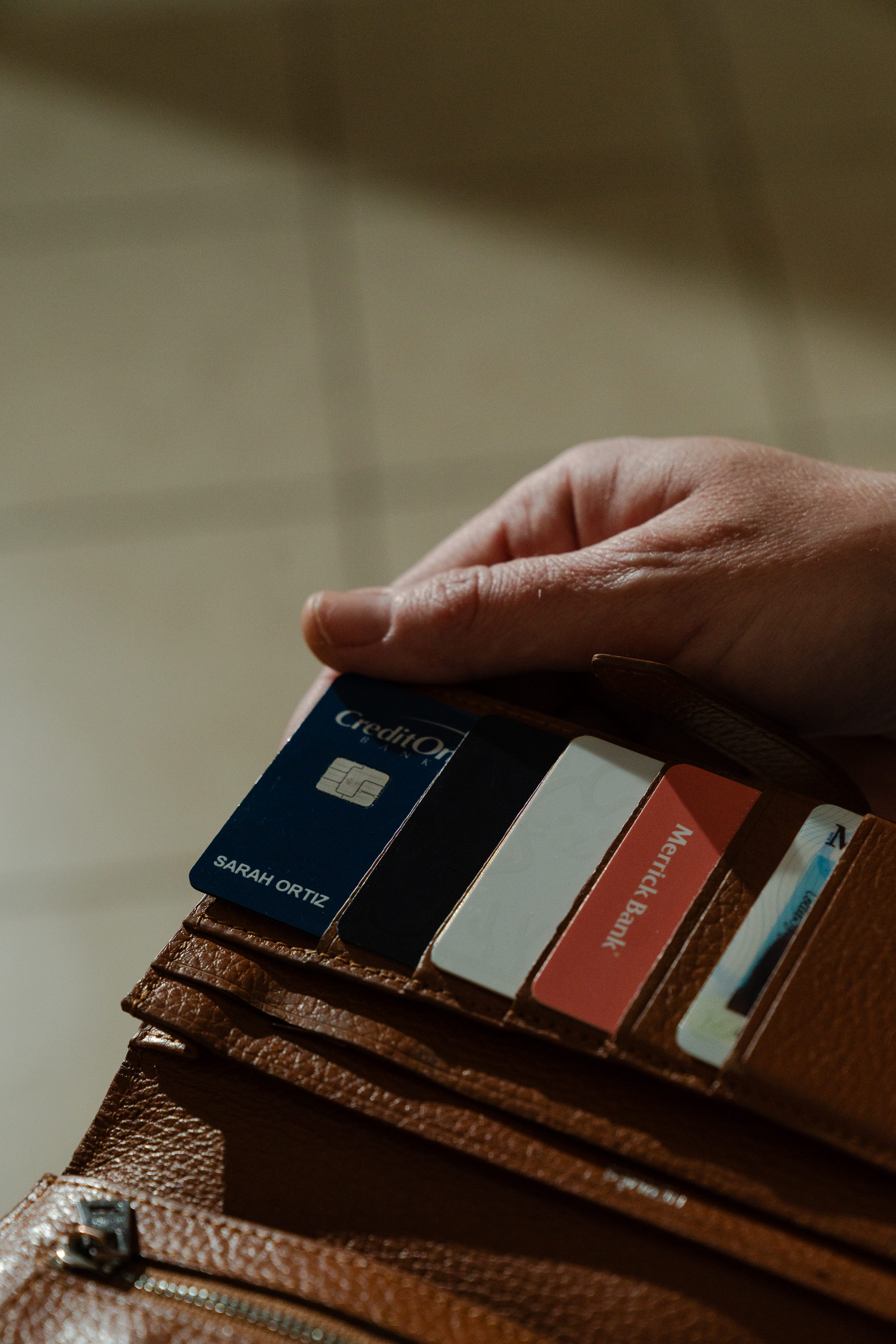 Close-up of a woman's hand holding a wallet with credit cards.