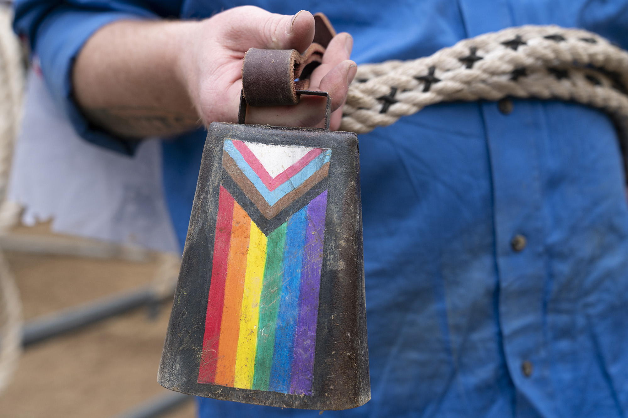 Close-up of a cowbell with a rainbow flag painted on it.