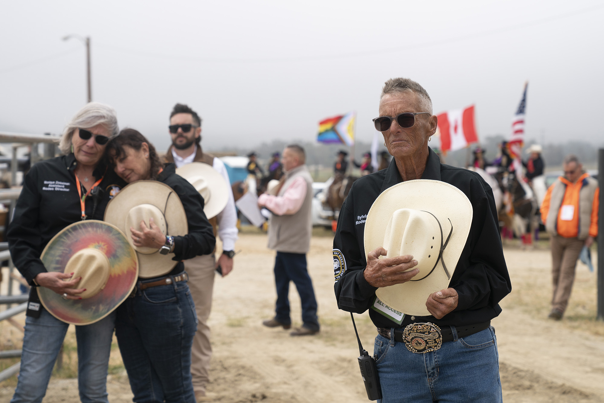 Group of people standing, holding cowboy hats over their hearts.