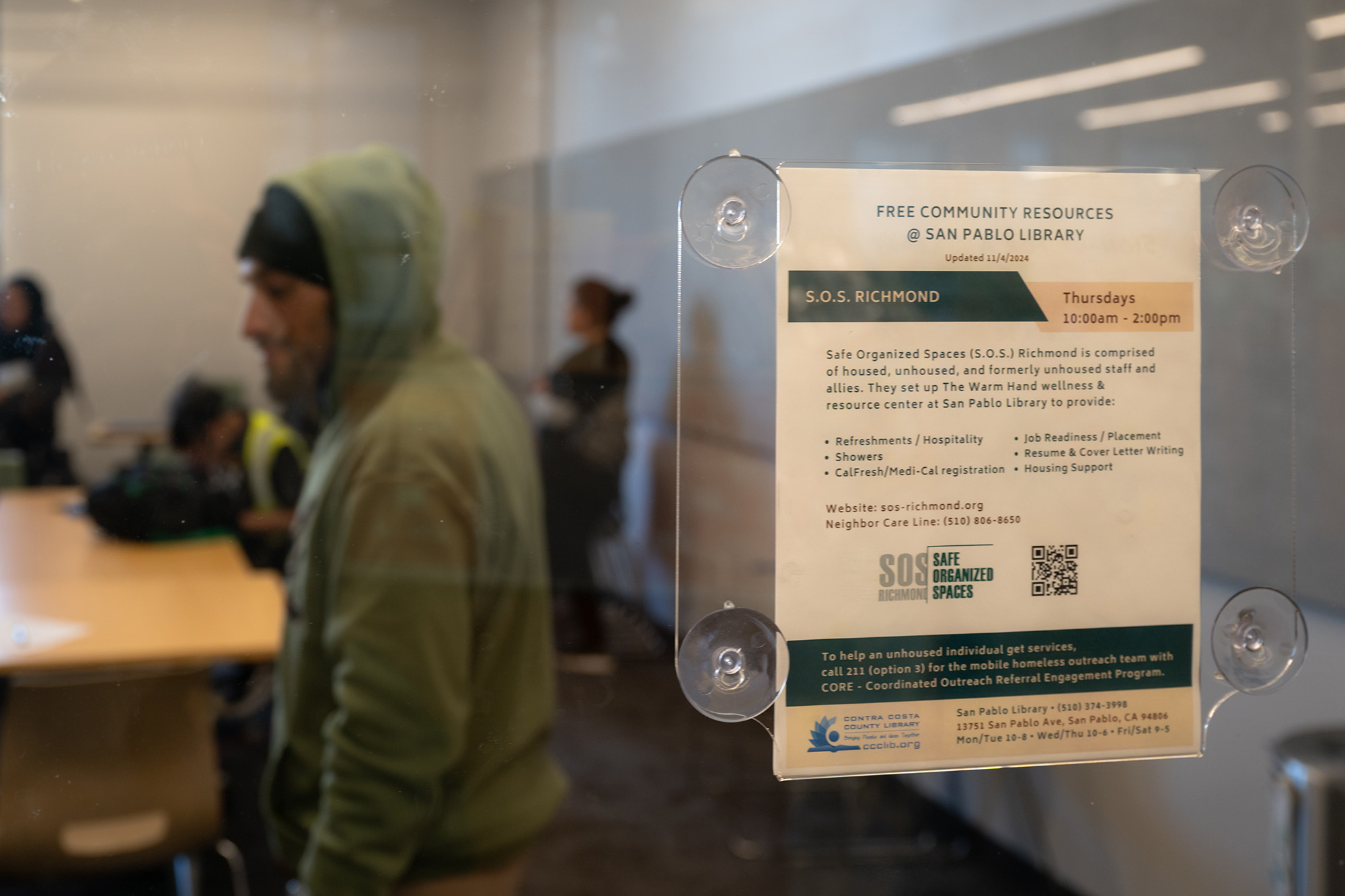 A sign in a window that details free community resources of SOS Richmond at a local library.
