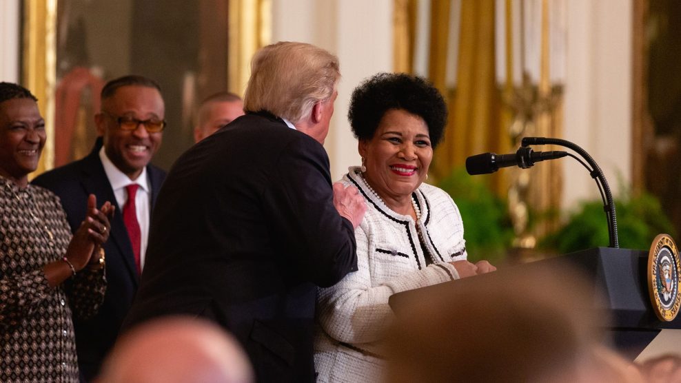 Alice Marie Johnson stands at a podium while Donald Trump talks to her.
