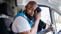 A black man dabs sweat away from his head.