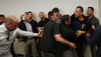 a blurry image with Padilla in focus being forced out of a DHS press conference