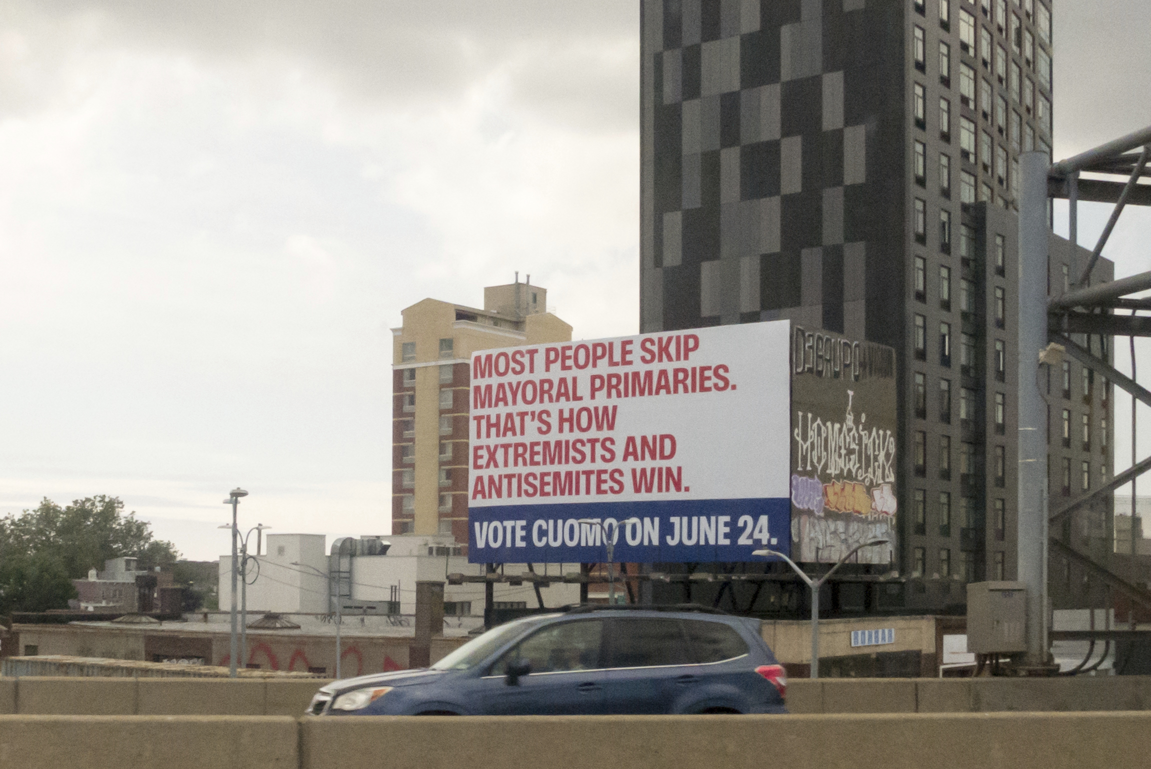 Cars drive past a billboard for candidate Andrew Cuomo