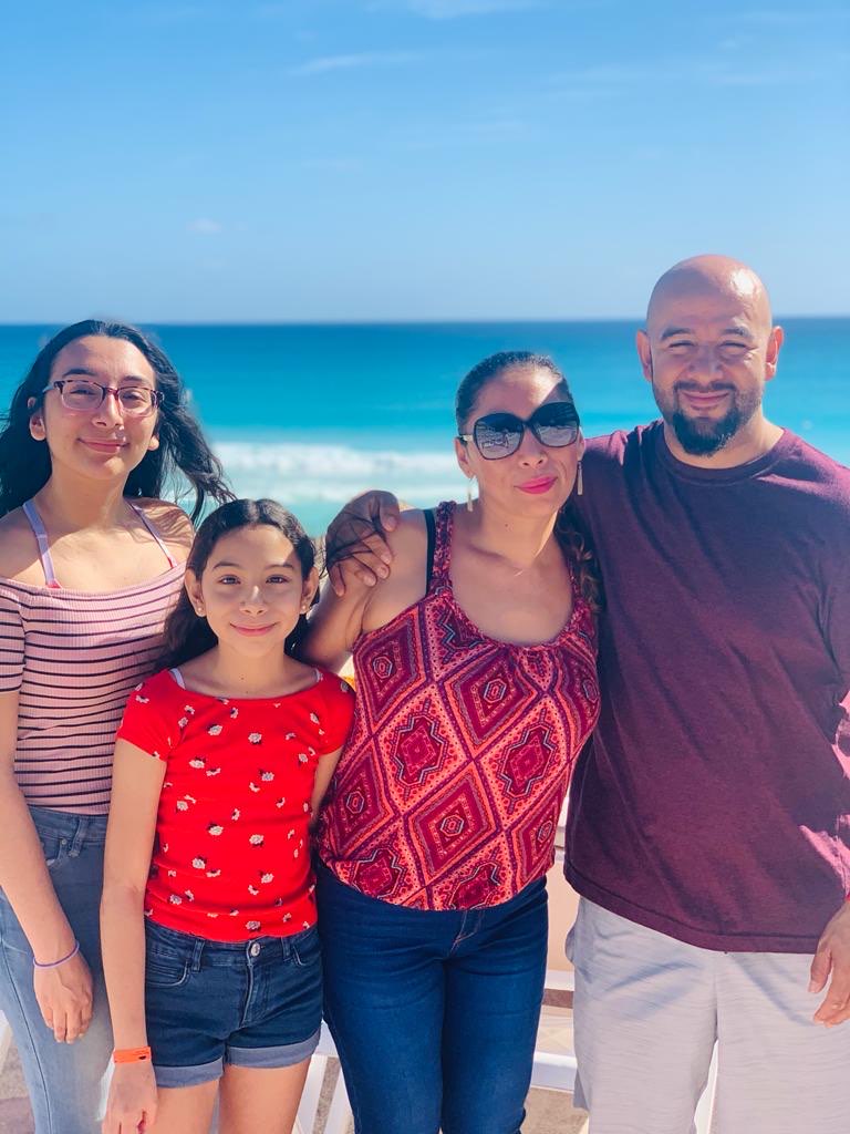 Two young girls stand with their mother and father on the beach