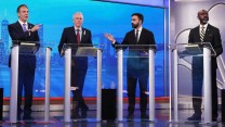 Four men stand at daises. Andrew Cuomo, left, and Zohran Mamdani, second from right, gesture in each other's directions.