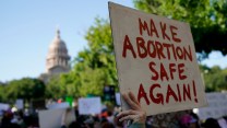 Person holds sign reading 'Make Abortion Safe Again!' outside Texas Capitol building.