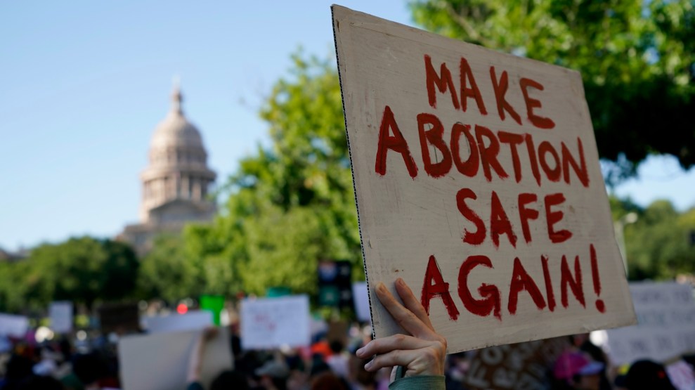 Person holds sign reading 'Make Abortion Safe Again!' outside Texas Capitol building.
