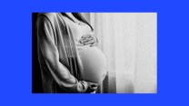 A photo of a pregnant woman dressed in a shawl with her hands on her belly.