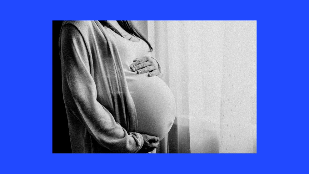 A photo of a pregnant woman dressed in a shawl with her hands on her belly.